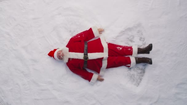 Santa Claus maken een sneeuw engel — Stockvideo