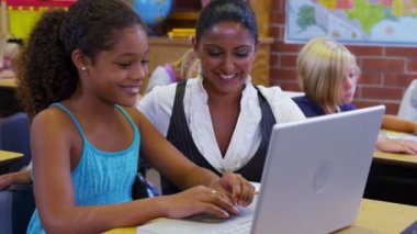 Öğretmen öğrenci bilgisayar ile yardımcı olur