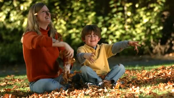 Семья играет в осенние листья — стоковое видео