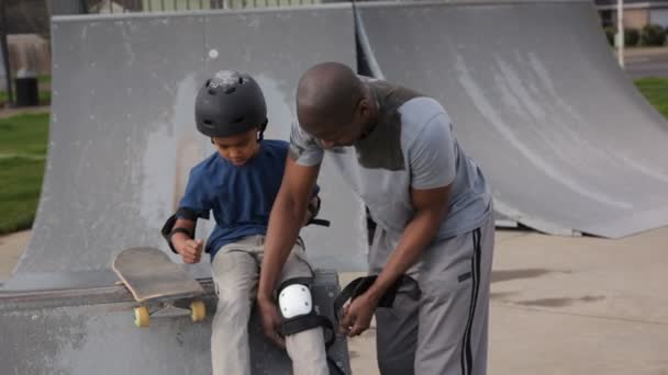 Padre ayudando a su hijo a conseguir seguridad skateboard — Vídeos de Stock