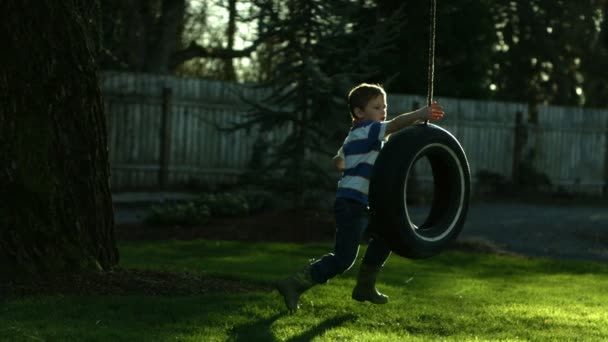 Garçon jouer sur pneu swing — Video