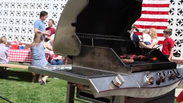 Человек готовит бургеры и сосиски — стоковое видео