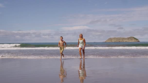 Мать и сын бегут по пляжу — стоковое видео