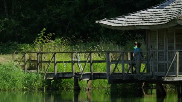 Dos jóvenes caminando en el muelle en el lago — Vídeo de stock