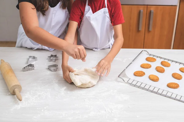 Küçük ve kısa çocuklar mutfakta yumurta ve bisküvilerle hamur pişiriyorlar..