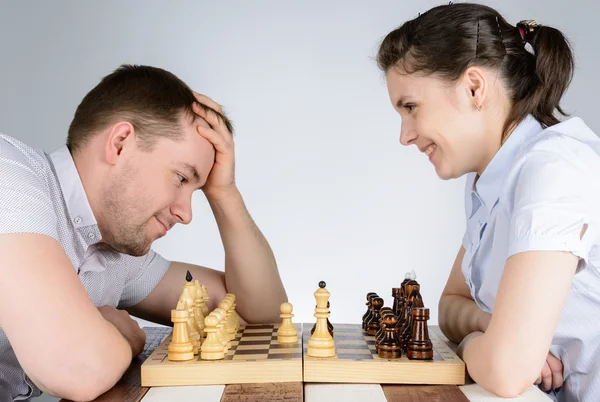 Žena se směje při hraní šachů proti napjatý muži — Stock fotografie