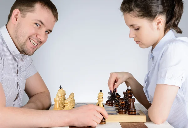 Kvinna som spelar svart bitar i schack mot de grinande män — Stockfoto