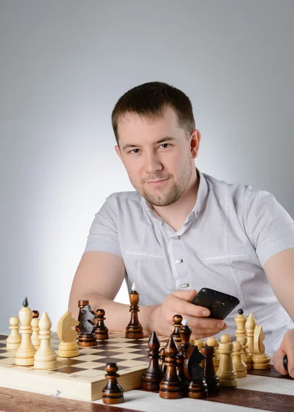 Man håller en telefon i deras händer och spela schack — Stockfoto