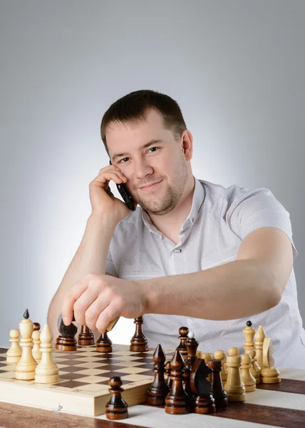 Man håller en telefon i deras händer och spela schack — Stockfoto