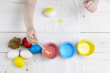 Çocuk yumurta Paskalya için ahşap masanın üzerine boya