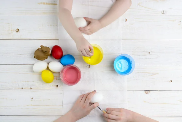 Children paint eggs for Easter on the wooden table — Stock Photo, Image