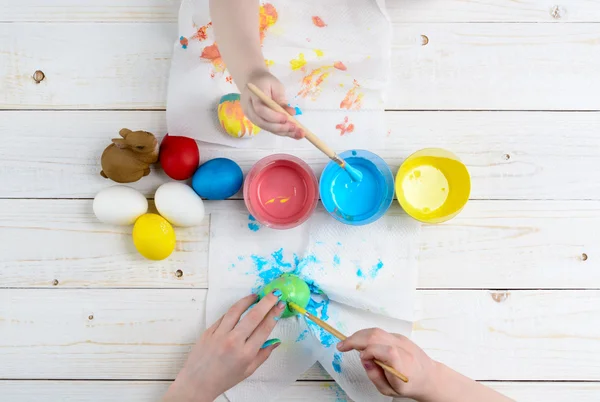 Children paint eggs for Easter on the wooden table — Stock Photo, Image