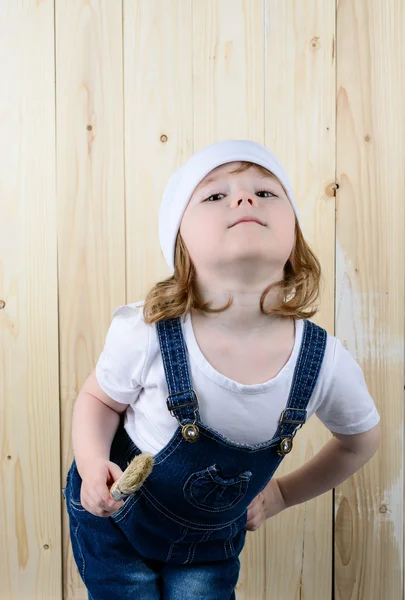 Fille posant avec une brosse dans un mur en bois — Photo