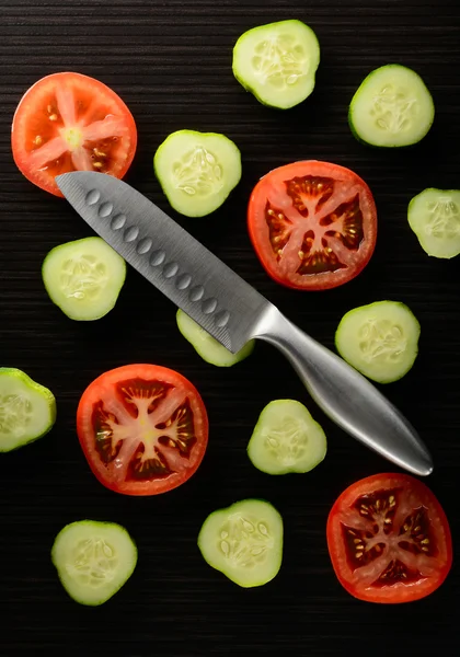 Cut tomato and cucumber with a knife — Stock Photo, Image