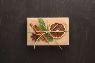 El işi kağıdına sarılı bir hediye kutusu ve ladin dalı, kurutulmuş portakal ve tarçınla süslenmiş..
