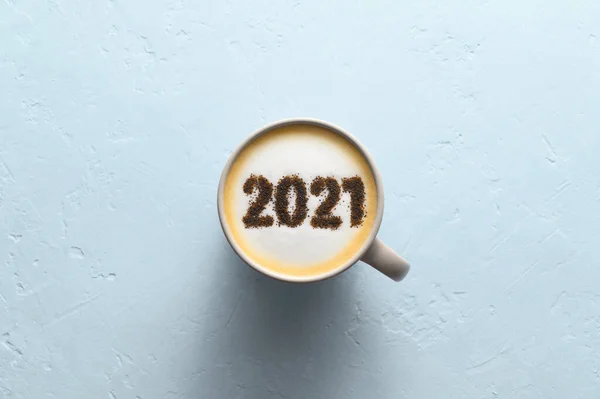 Číslo 2021 na zpěněném povrchu cappuccino v šálku kávy na pastelově modrém pozadí. Potravinový kreativní koncept — Stock fotografie