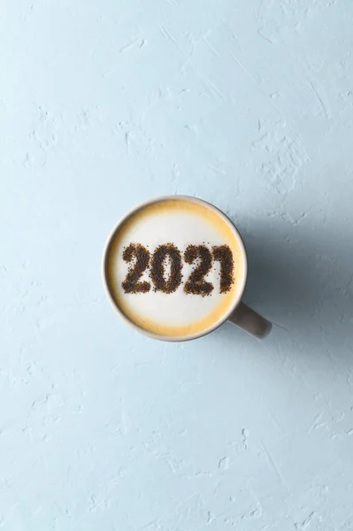 Číslo 2021 na zpěněném povrchu cappuccino v šálku kávy na pastelově modrém pozadí. Potravinový kreativní koncept — Stock fotografie