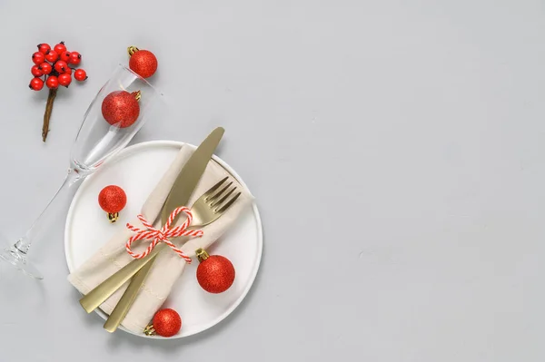 Ünnepi asztalterítés fehér tányérral, arany evőeszközökkel és karácsonyi dekorációkkal világosszürke asztalon — Stock Fotó