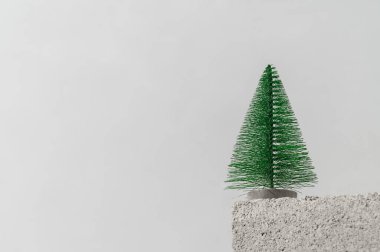 Taş kürsüsü ve gri arka planda xmas ağacı olan minimum kompozisyon. Boşluğu kopyala, metin için yer