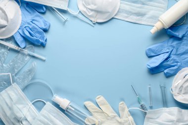 Kullanılmış tıbbi yüz maskeleri, lateks eldivenler, şırıngalar, pastel mavi arka planda test tüpleri. Coronavirus COVID-19 salgını sırasında çevresel kirlilik sorunu. Düz yatış, metin için yer