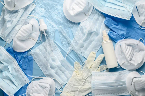 Used disposable medical face masks, latex gloves, syringes, test tubes on pastel blue background. Problem of environmental pollution during pandemic of coronavirus. COVID-19 waste. Top view, close up