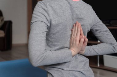 Genç bir kız spor yapıyor, evde yoga yapıyor. Sağlıklı yaşam tarzı kavramı. Evde idman yapıyorum. Ev içi, gündüz..
