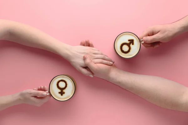 Süt köpüğünün üzerinde Venüs ve Mars sembolleri olan iki fincan kahve ve birbirine aşık çiftlerin el ele tutuşmaları. — Stok fotoğraf