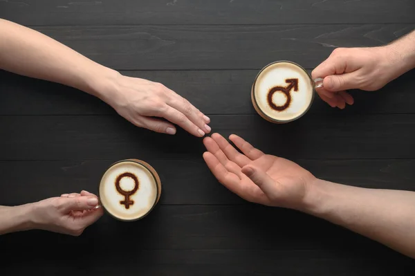 Twee kopjes koffie met symbolen van venus en mars op melkschuim en hand in hand van verliefd koppel op donkere houten tafel — Stockfoto