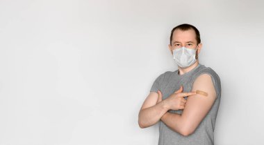 Koruyucu yüz maskesi takan genç bir adam aşıdan sonra kolunu gösteriyor. Salgın covid-19 sırasında tema bağışıklığı. Metin için boşluk, seçici odak