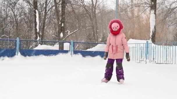 Bambina in giacca rosa che impara a pattinare sul ghiaccio — Video Stock