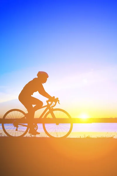 Unrecognizable silhouette man riding bicycle against sunset sky — Stock Photo, Image