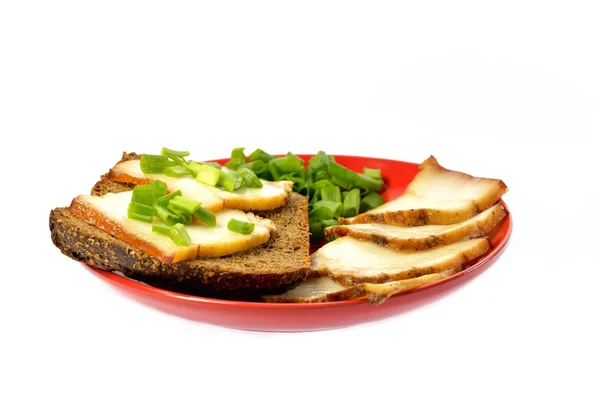 Plato rojo con un pedazo de pan y tocino — Foto de Stock