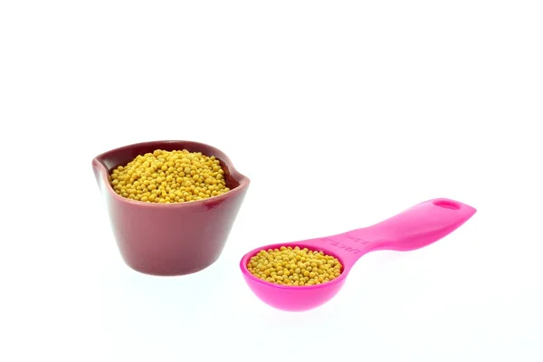 Mustard seeds in a cup and measuring spoon — Stock Photo, Image