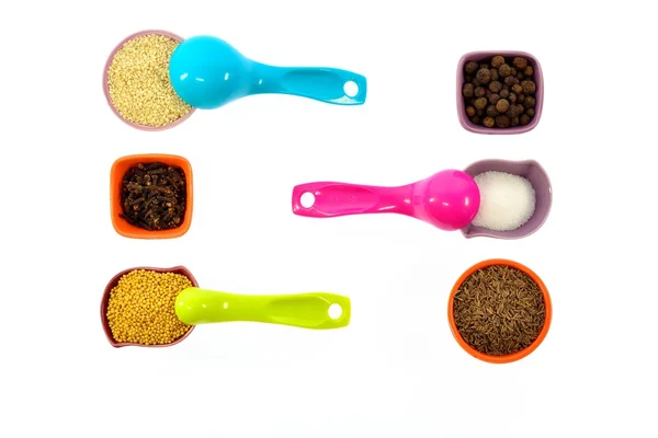 Sementes, especiarias, grãos em pequenos copos multicoloridos e colheres de medição — Fotografia de Stock