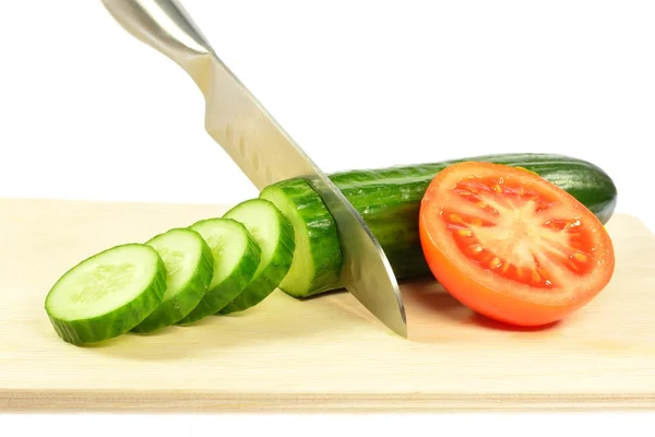 Het mes gesneden komkommer in reepjes naast een halve tomaat — Stockfoto