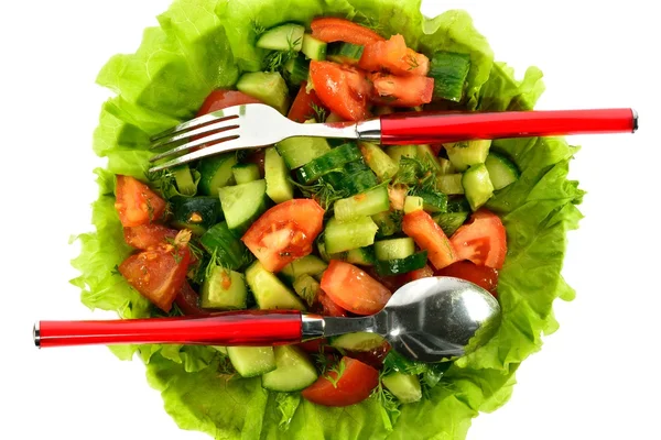 Salad of tomatoes, cucumbers and dill on lettuce leaves with a spoon and fork — Stock Photo, Image
