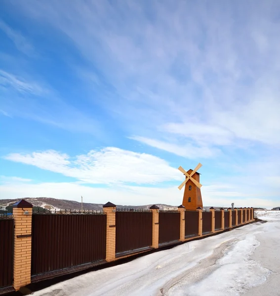 Větrný mlýn a hnědé plot na pozadí modré oblohy — Stock fotografie