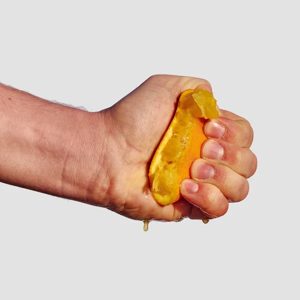 La mano del hombre exprime el jugo de la naranja — Foto de Stock