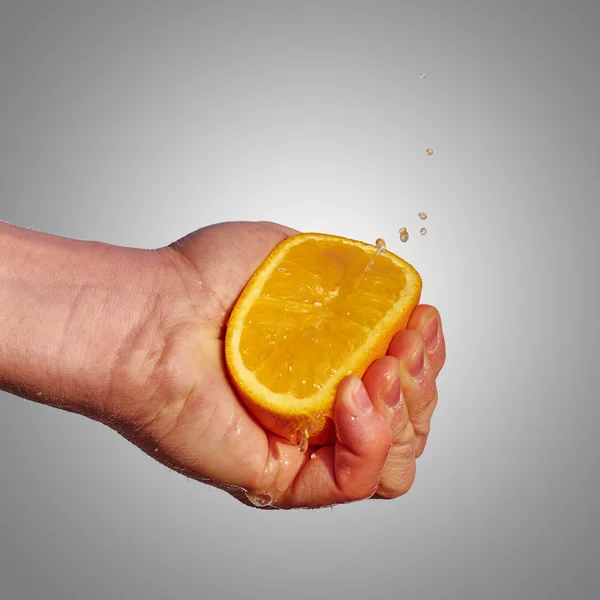 La mano dell'uomo stringe il succo dall'arancia — Foto Stock