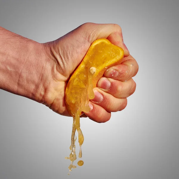 A mão do homem espreme o suco da laranja — Fotografia de Stock