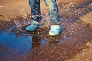 Çocuk bir su birikintisine atlar