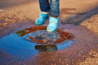 Çocuk bir su birikintisine atlar