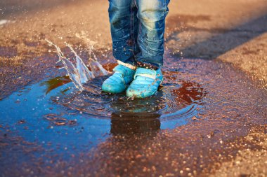 Çocuk bir su birikintisine atlar