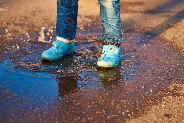 The child jumps in a puddle