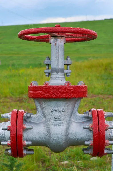 Ventil-Öl-Pipeline aus nächster Nähe vor grünem Gras und blauem Himmel — Stockfoto