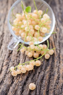 Ahşap masa üzerinde şeffaf bir fincan kuş üzümü