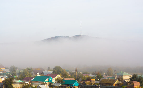 View of the village under the hill in the fog at dawn