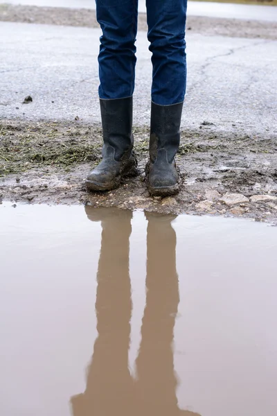 Riflessione di piedi in stivali fangosi una pozzanghera — Foto Stock