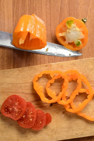 Couper la tomate et le poivre sur une planche de bois — Photo