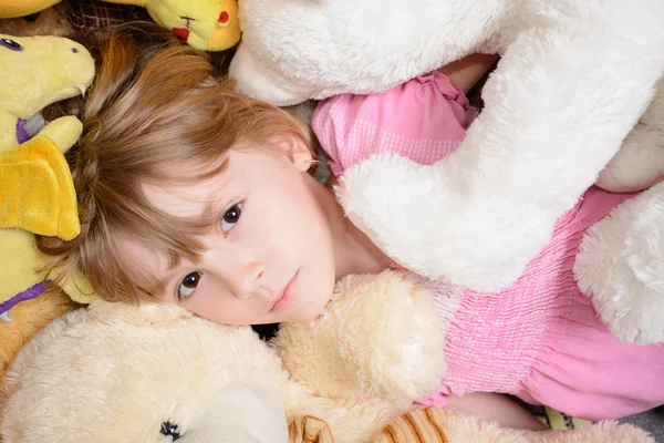 Маленька дівчинка лежить серед опудала іграшок — стокове фото